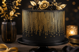 A black frosted cake with vertical gold stripes and gold dot patterns, decorated with a gold rose and gold leaves on top, displayed on a black cake stand against a dark background with warm bokeh lights.